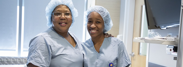 A mentor and her student wear scrubs in a healthcare setting